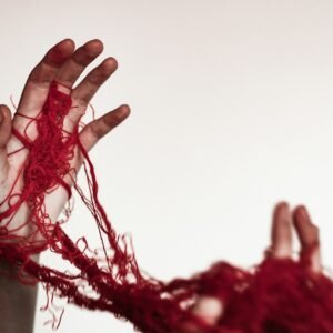 A person with their hands wrapped in red yarn