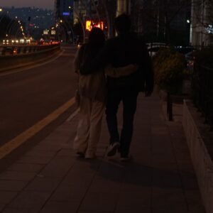 two people walking down a sidewalk at night