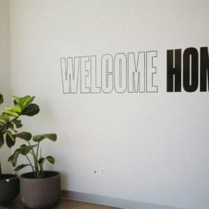 A white wall with a sign that says welcome home