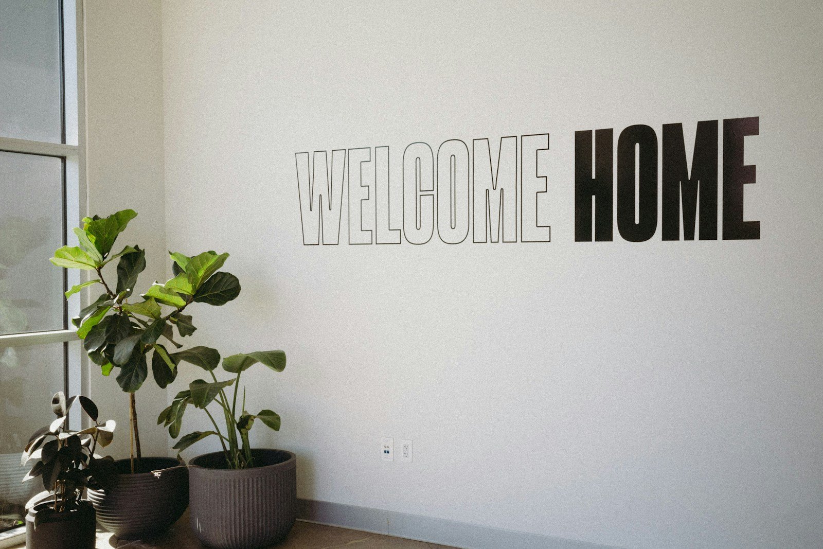 A white wall with a sign that says welcome home